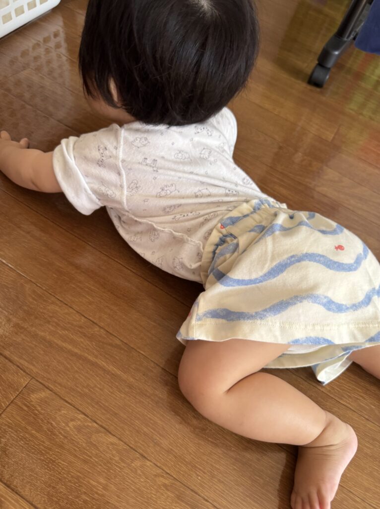 コンビ肌着にお下がりの短パンを合わせて、ずり這いする生後9ヶ月の赤ちゃん