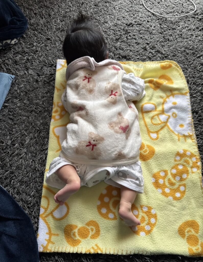 コンビ肌着にくま柄の半纏を重ねた生後2ヶ月の赤ちゃん