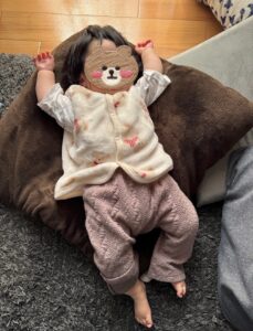 コンビ肌着にくま柄のもこもこ前開きとピンクのキルトパンツを重ねた生後5ヶ月の赤ちゃん