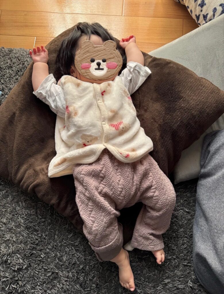 コンビ肌着にくま柄のも半纏とキルトパンツを重ねた生後5ヶ月の赤ちゃん