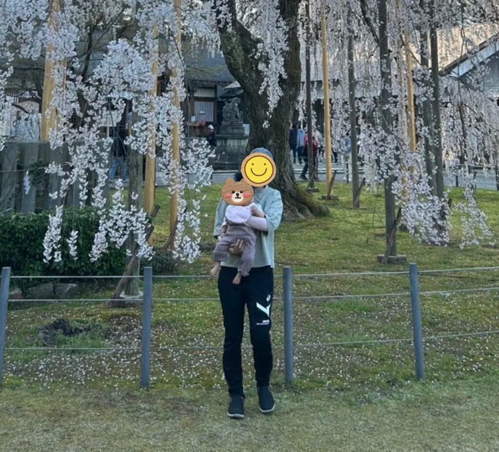 桜の下で赤ちゃんを抱っこする様子(お花見の日の全身)