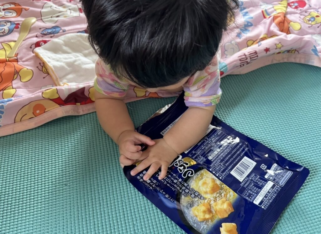 知育玩具やその他おもちゃよりも、お菓子の袋で遊ぶ、生後9ヶ月の赤ちゃん。