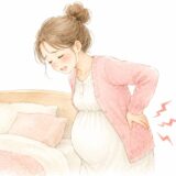 妊娠中にぎっくり腰になり、ベッドのそばで腰を押さえる妊婦さんのイラスト