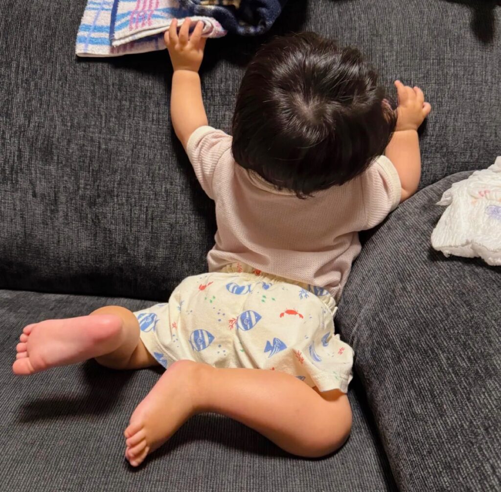 肌着のボディスーツの上に短パンを履いた生後11ヶ月の赤ちゃんの後ろ姿