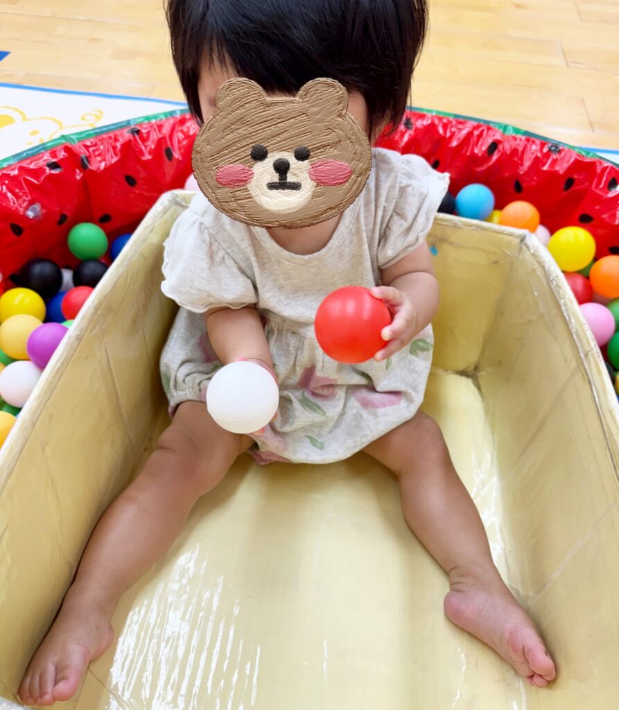 ハイレグ型ロンパースを着て、おでかけ先のボールプールで遊ぶ生後11ヶ月の赤ちゃん